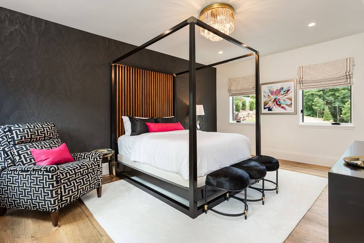 Bedroom with black canopy bed frame and graphic black and white armchair