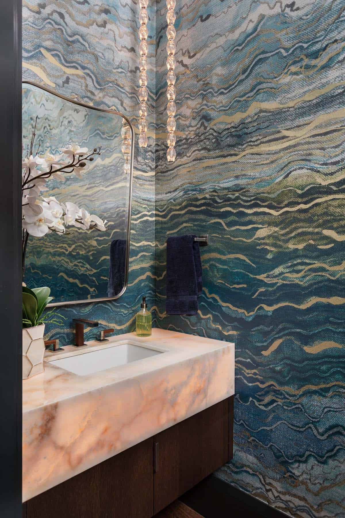 Powder room vanity closeup with blue wave wallpaper and beaded pendant lights
