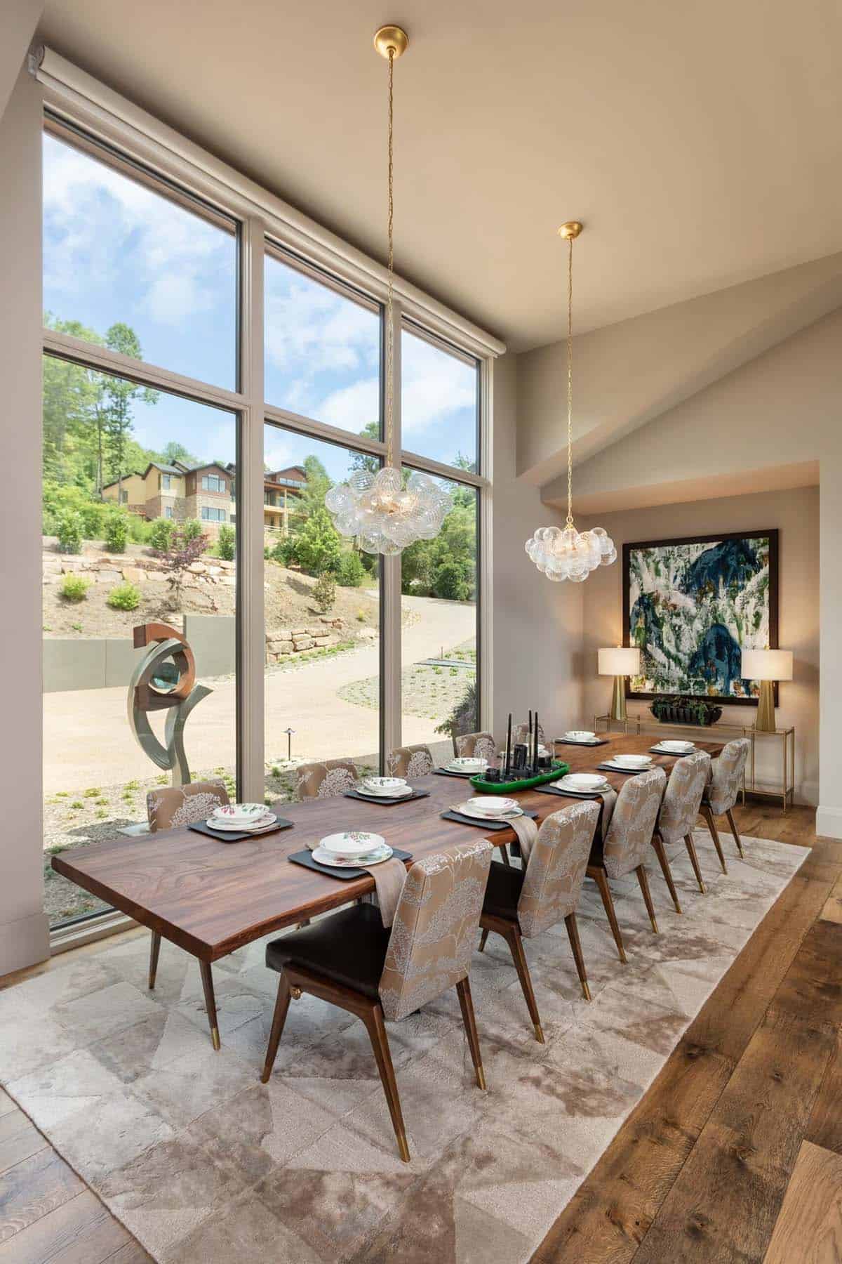 Long dining table facing floor to ceiling windows and hillside sculpture view