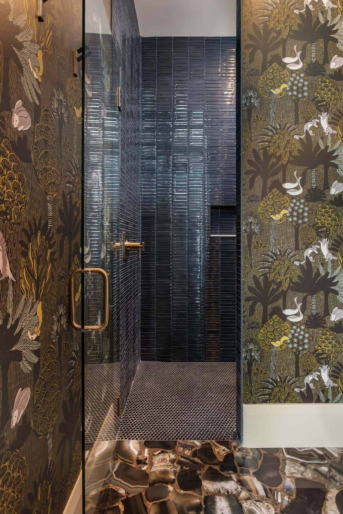Powder room glass door framed by dark botanical wallpaper and agate floor