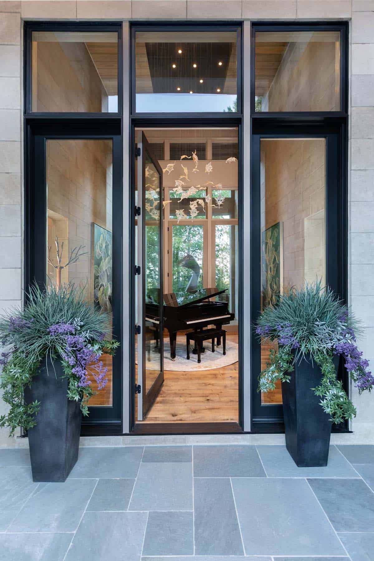 Front entry view through open door toward grand piano and glass chandelier