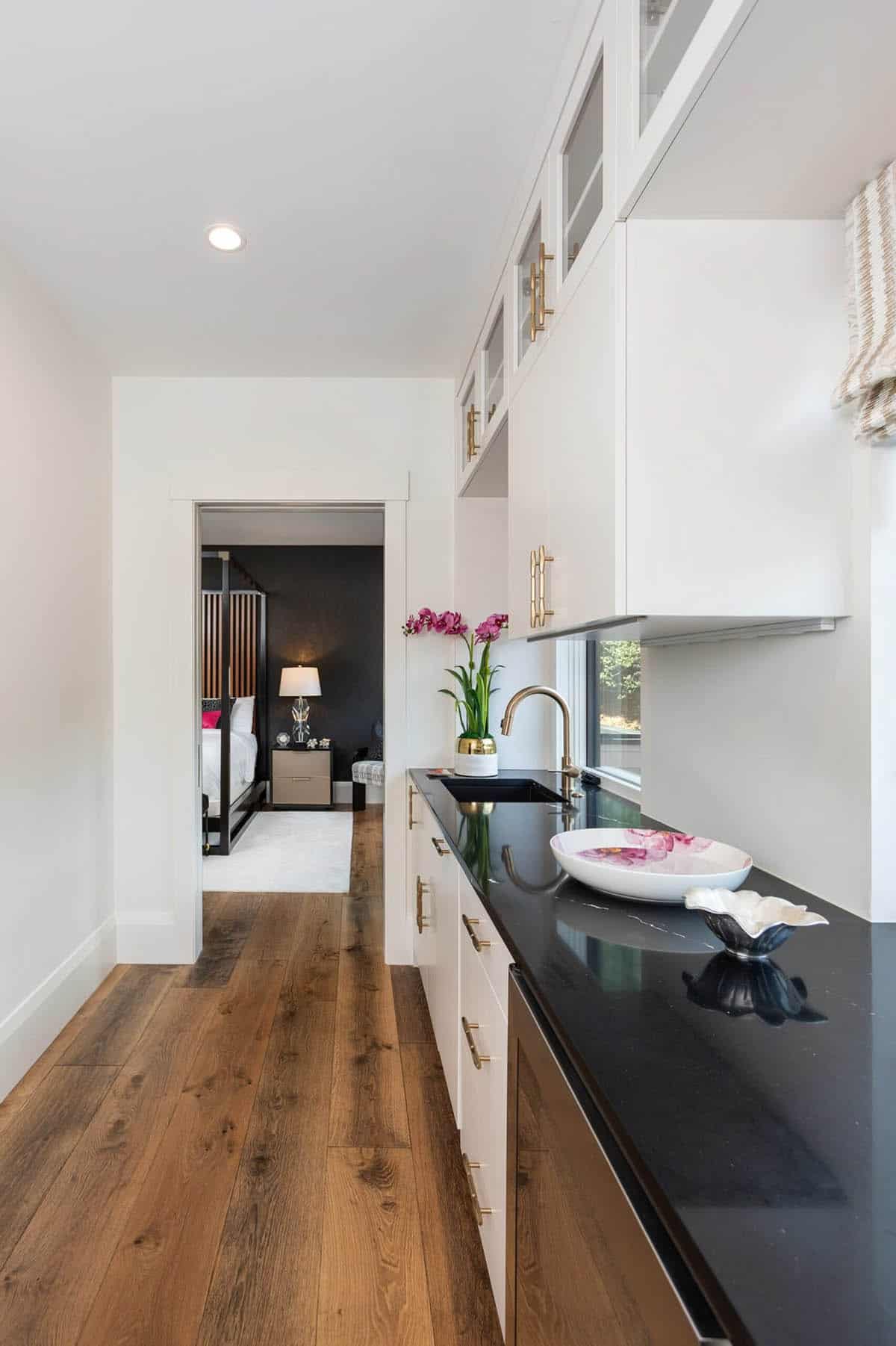 Butler pantry hallway with black countertop leading to dark canopy bedroom