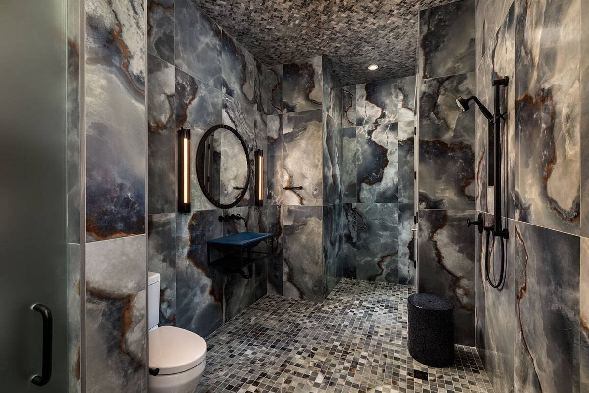 Onyx clad steam shower with floating blue vessel sink and mosaic tile