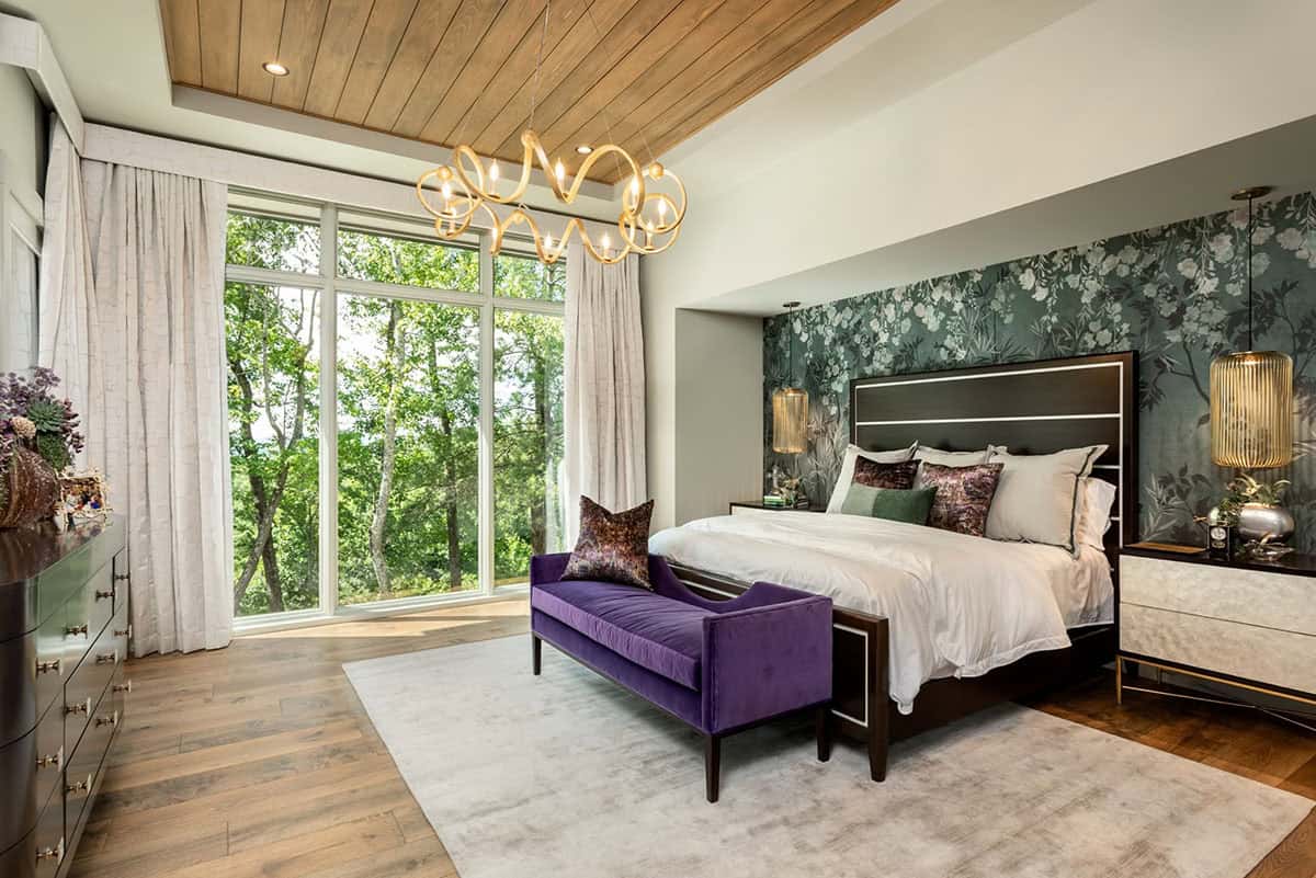 Primary bedroom with wood ceiling, purple velvet bench, and floral accent wall