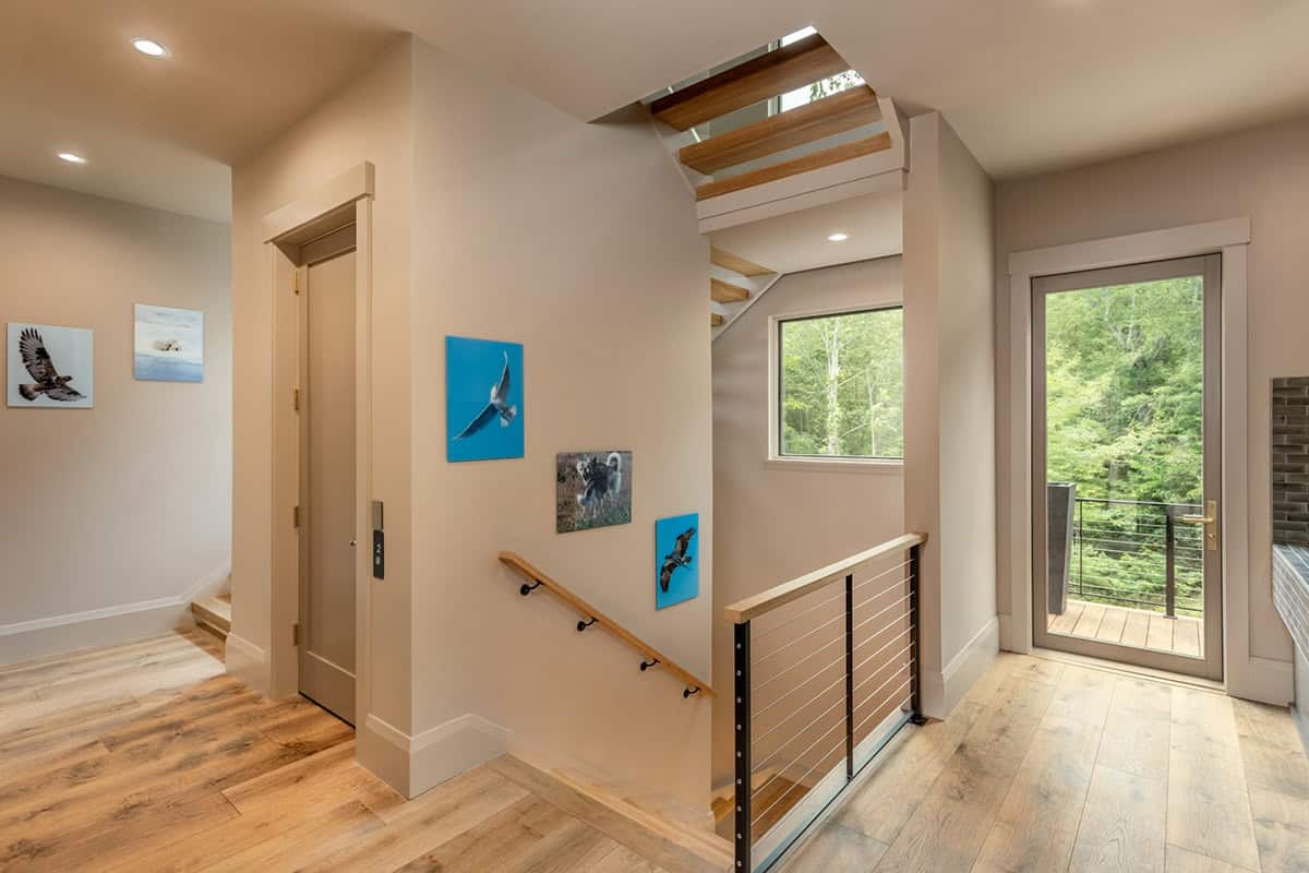 Stairway landing with cable railing and framed wildlife photography on wall