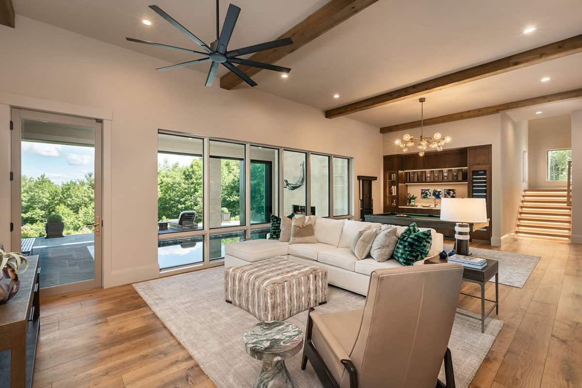 Family room with white sectional facing pool view and wood beam ceiling