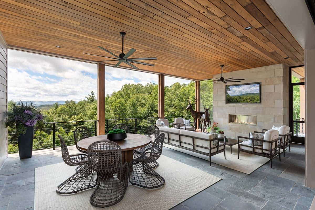 Covered deck with woven dining set, sectional, and stone fireplace wall