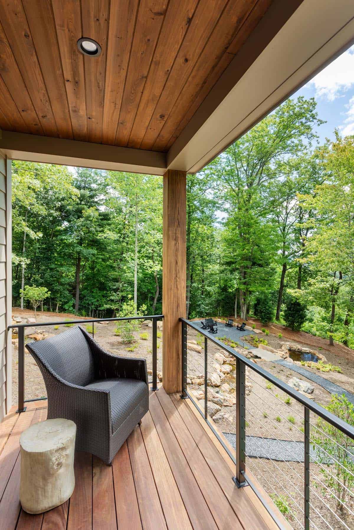 Screened porch with woven armchair overlooking sloped native landscaping