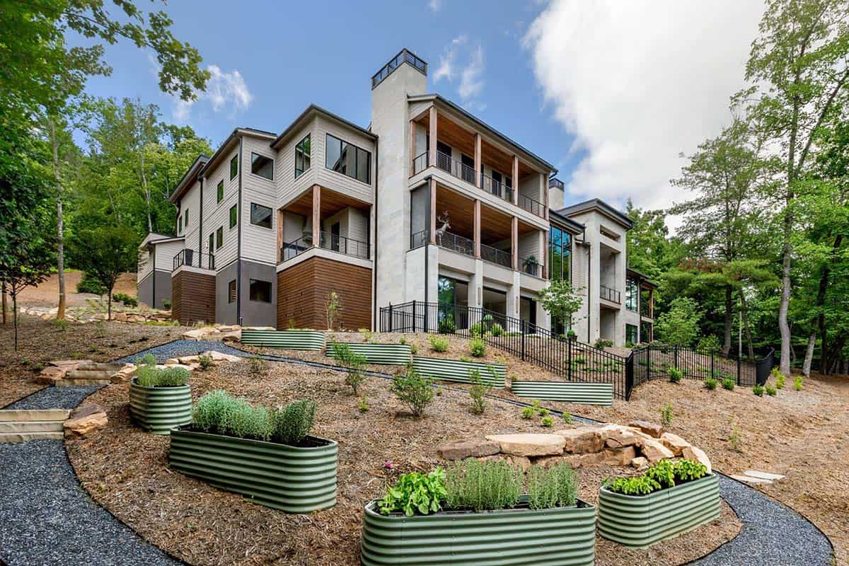 Rear exterior with stacked balconies, raised garden beds, and wooded slope