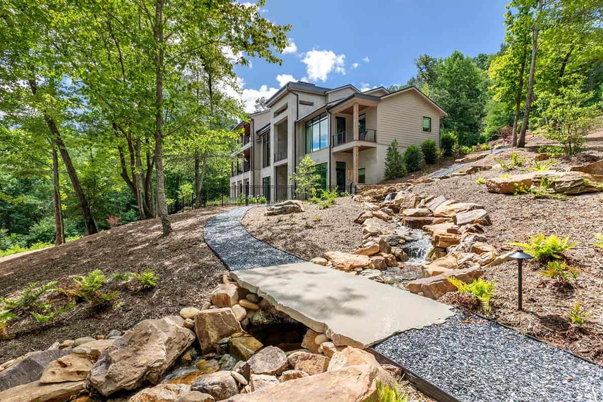 Rear exterior with rock lined stream and stepping stone path to home