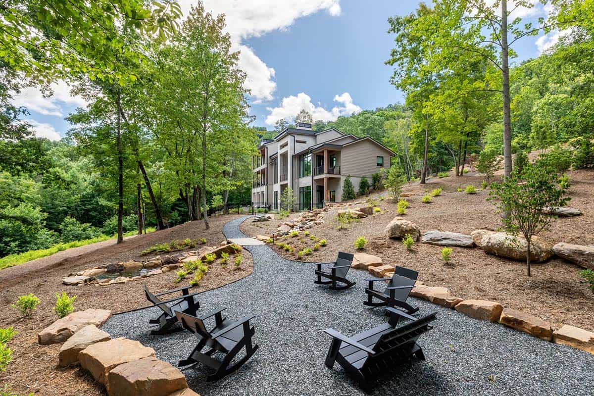 Backyard gravel fire pit seating area facing wooded hillside path