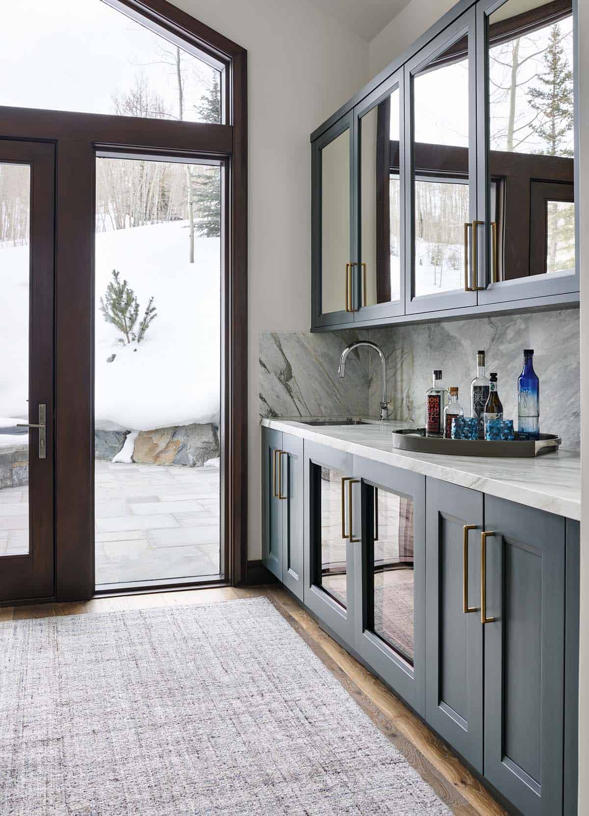 Butler's pantry with slate-blue glass-front cabinets and mirrored backsplash near a patio door