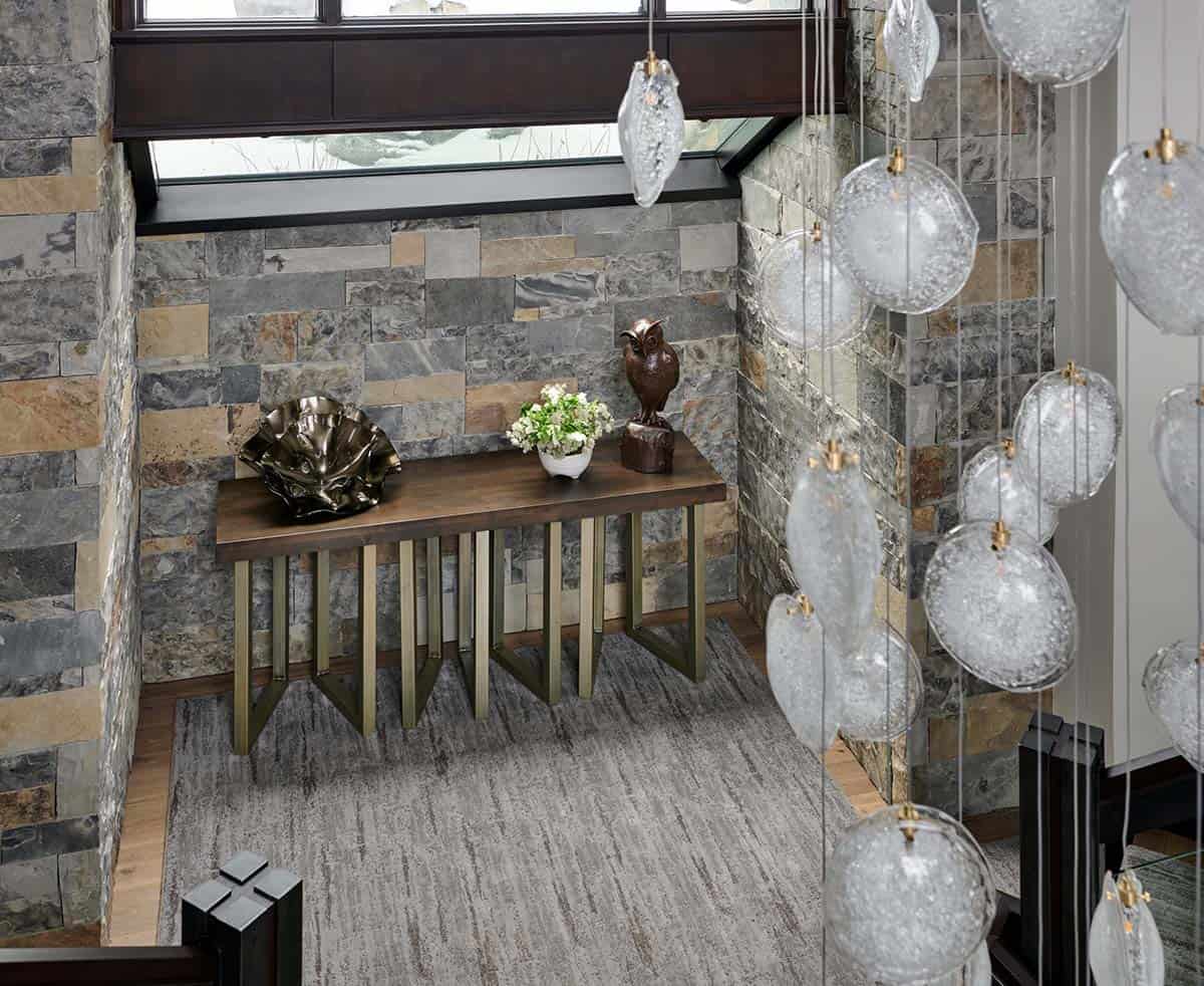 Stone-walled entry nook with wood console table and hanging glass pendant lights