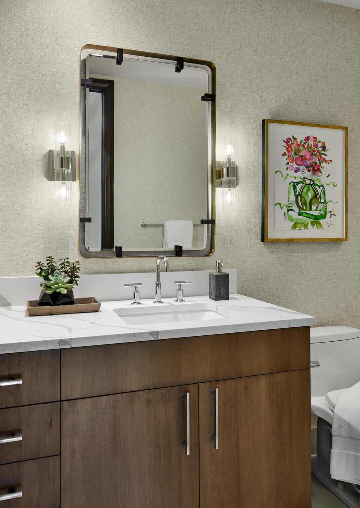 Bathroom vanity with wood cabinetry, marble countertop, and framed floral artwork