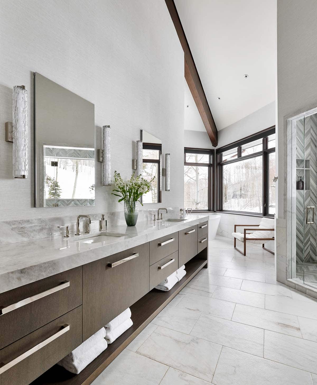 Primary bathroom with long double vanity, freestanding tub, and vaulted ceiling