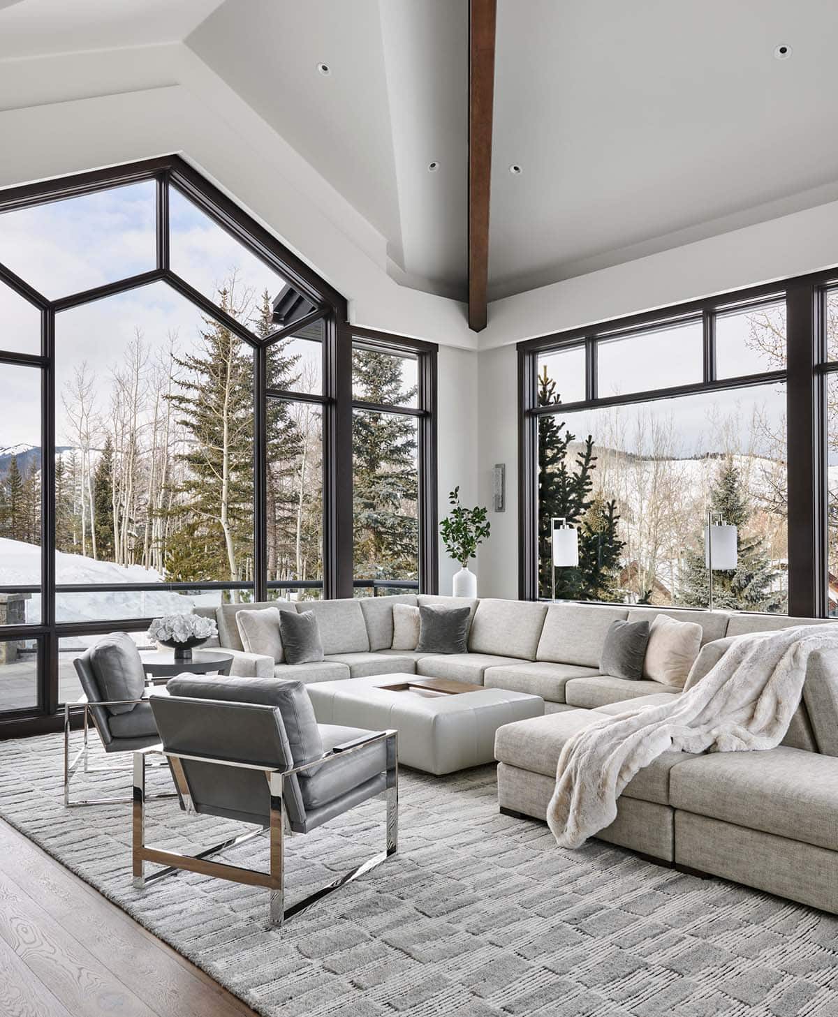 Living room with sectional sofa, geometric picture windows, and snowy mountain views