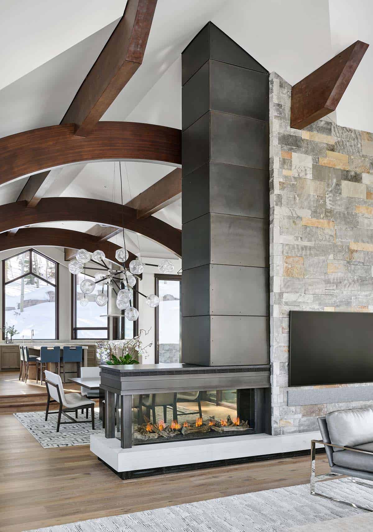 Double-sided fireplace with metal chimney surround opening to dining and living areas