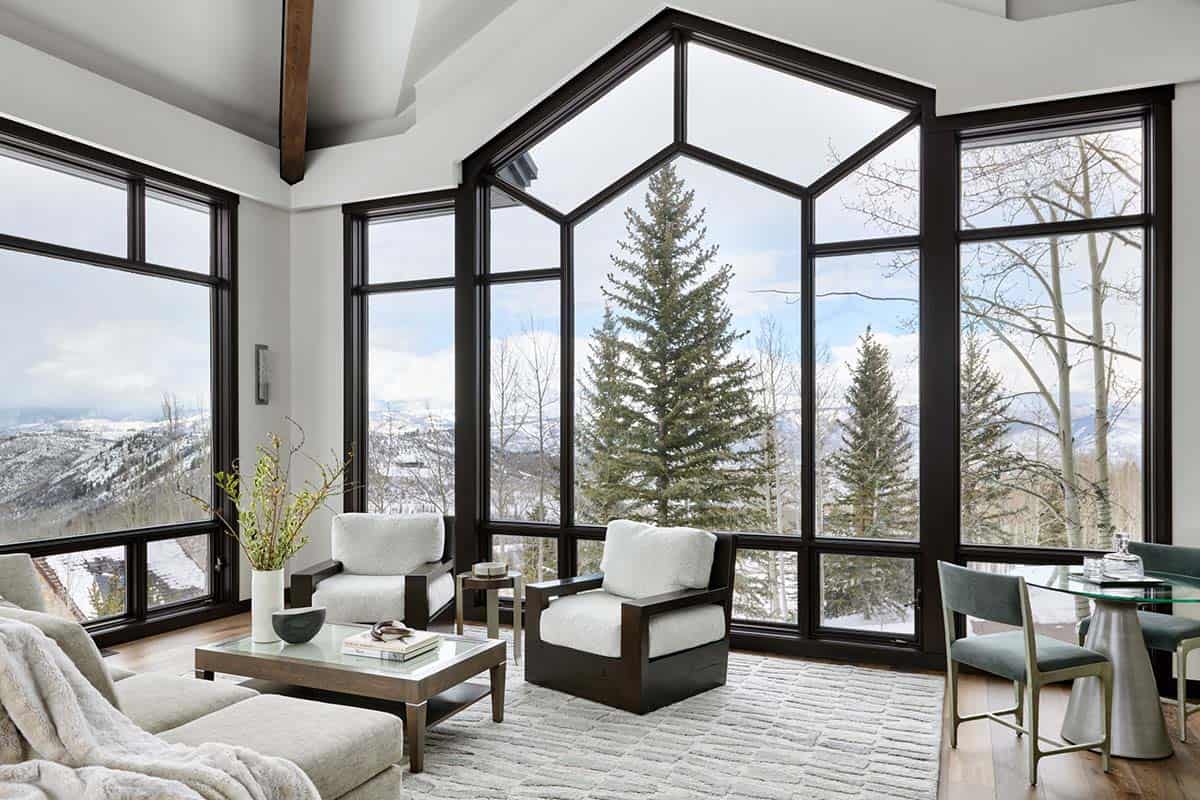 Living room corner with armchairs, glass coffee table, and dramatic geometric window wall