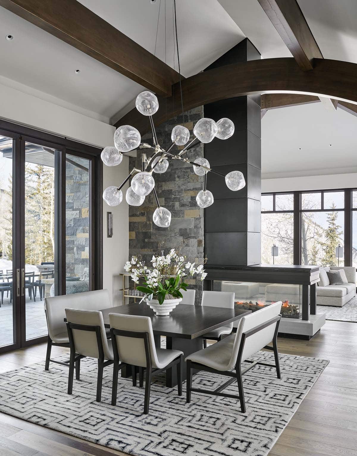 Dining table with orchid centerpiece beneath branching glass-bubble chandelier