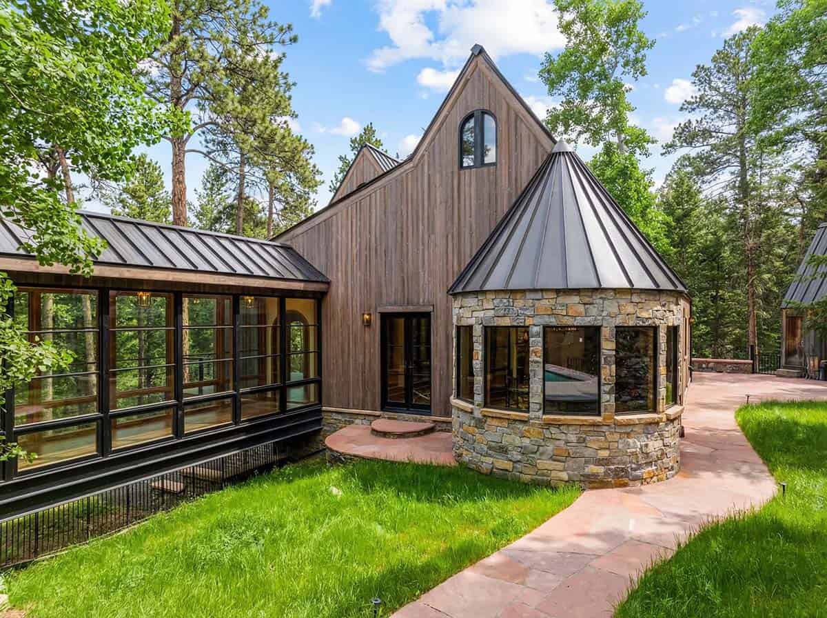 Round stone turret with conical roof beside glass-walled hallway