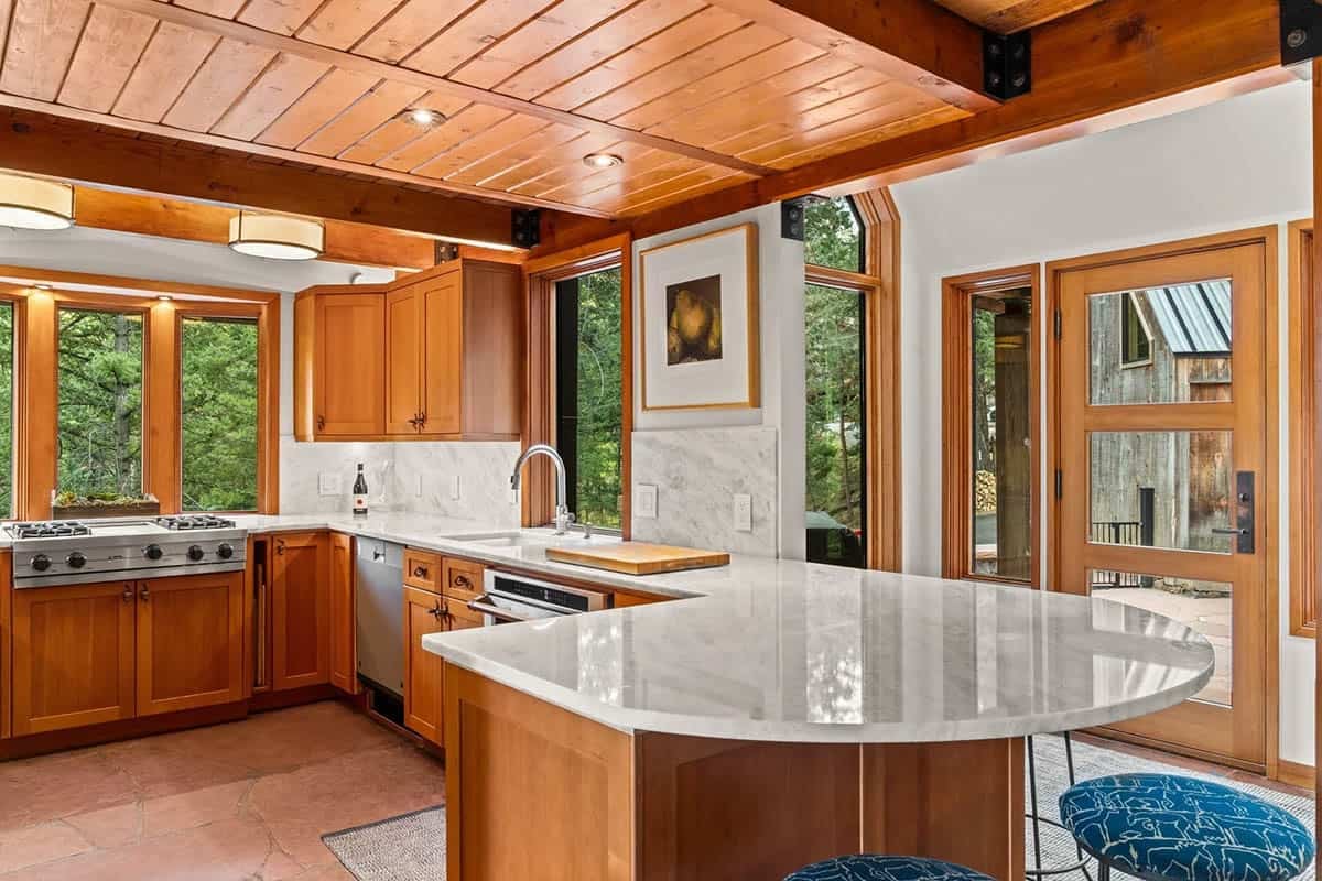 Kitchen island with white marble counter overlooks the forest view