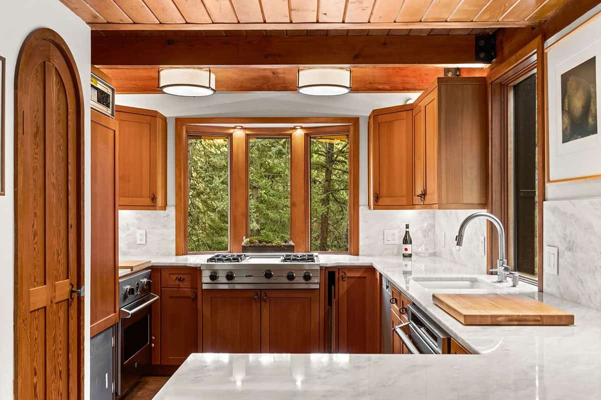 Kitchen bay window frames evergreens above the gas range