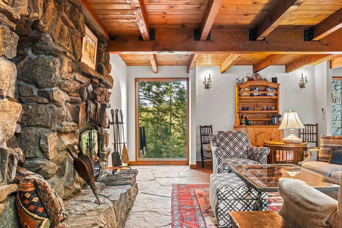 Stone fireplace anchors a cozy living room with patterned chairs
