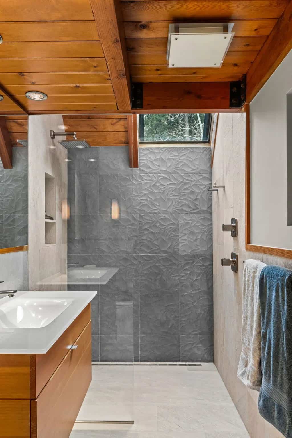 Modern bathroom shower features textured gray tile and wood ceiling