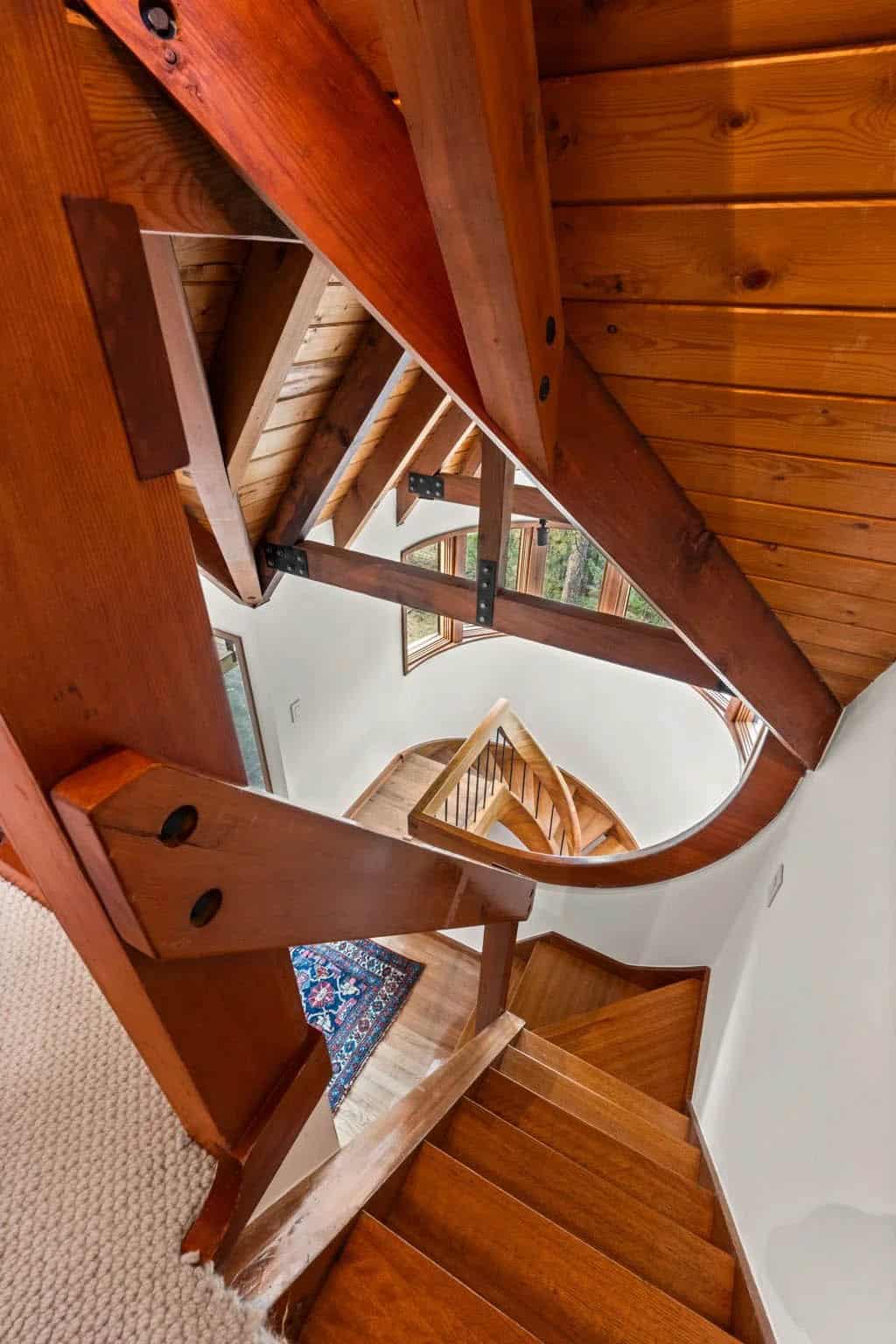 Overhead view of the curved wooden staircase and rug below