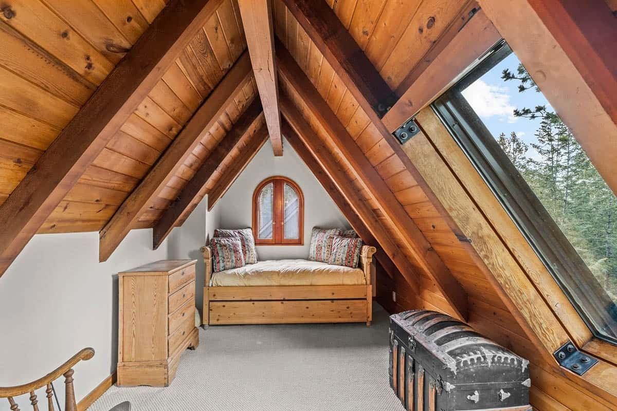 Cozy attic bedroom nook tucked beneath sloped wood beams