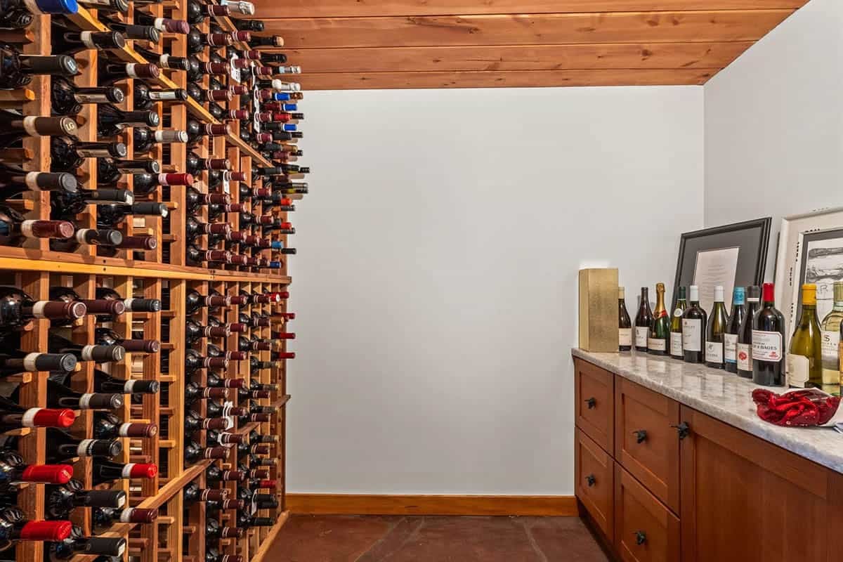 Wine cellar features floor-to-ceiling racks and a marble-topped bar