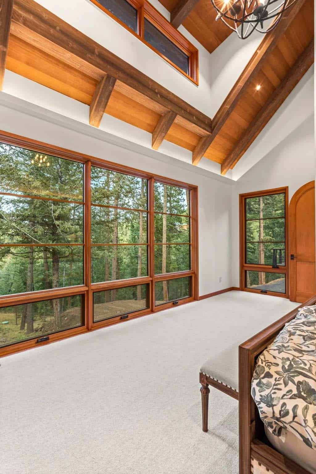 Vaulted bedroom corner with tall windows overlooking the pines