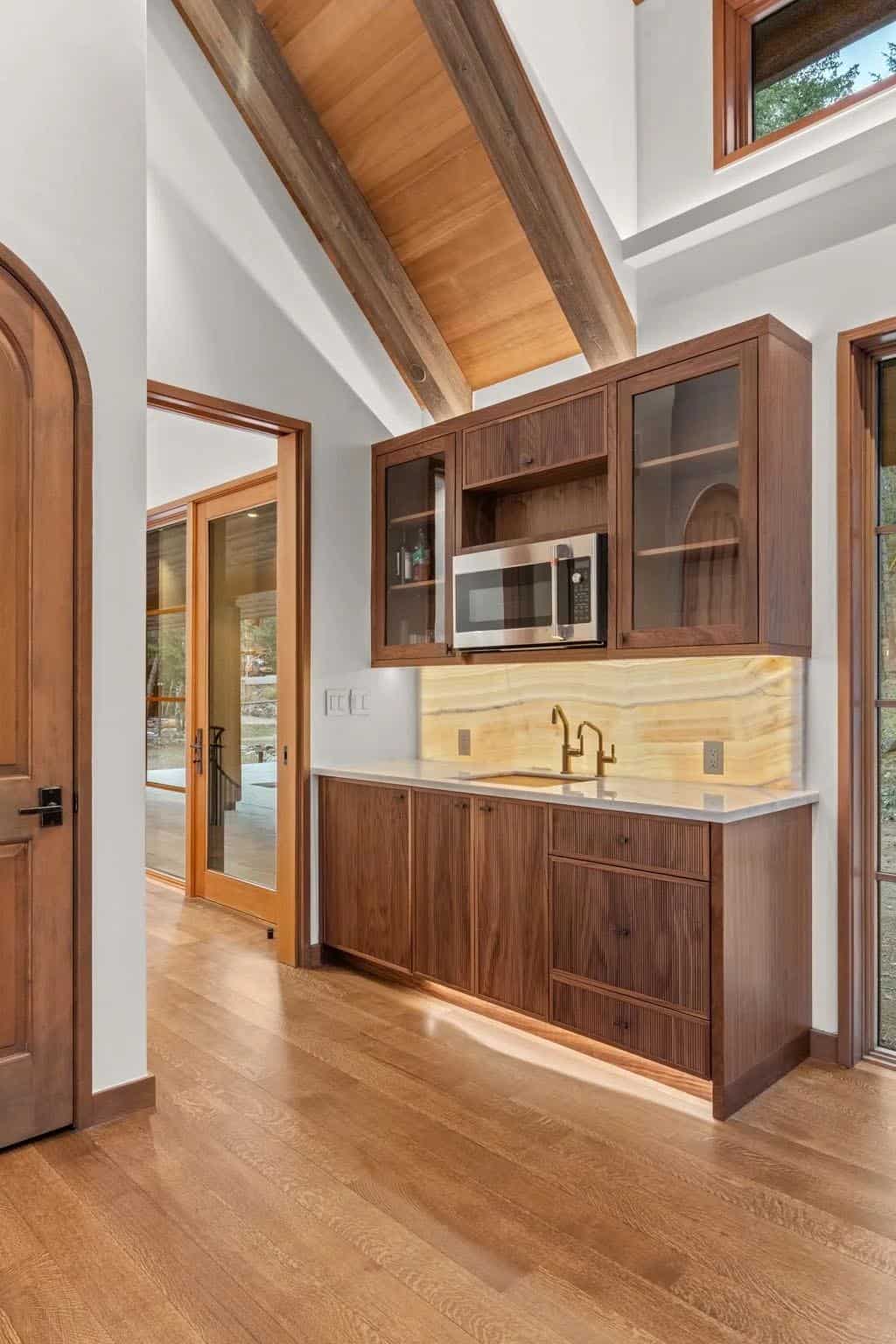 Wet bar features walnut cabinetry and a glowing onyx backsplash