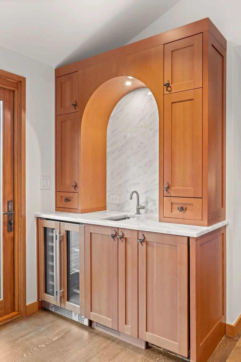 Arched wet bar niche with marble backsplash and wine fridge