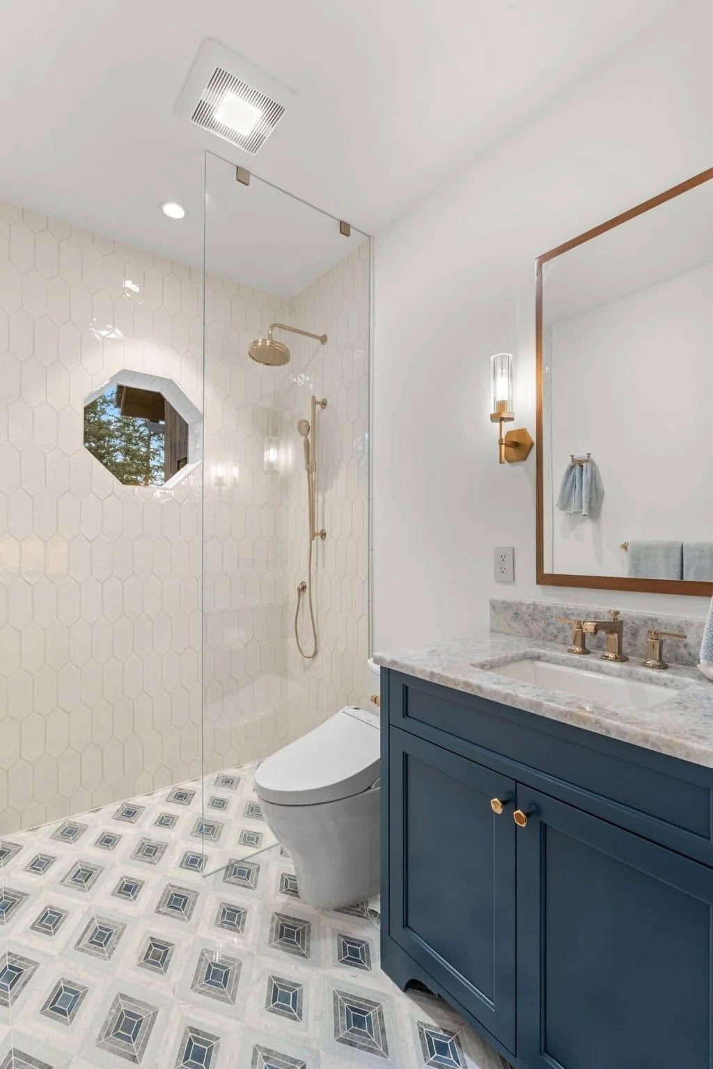 Guest bath features a navy vanity and hexagon tile shower