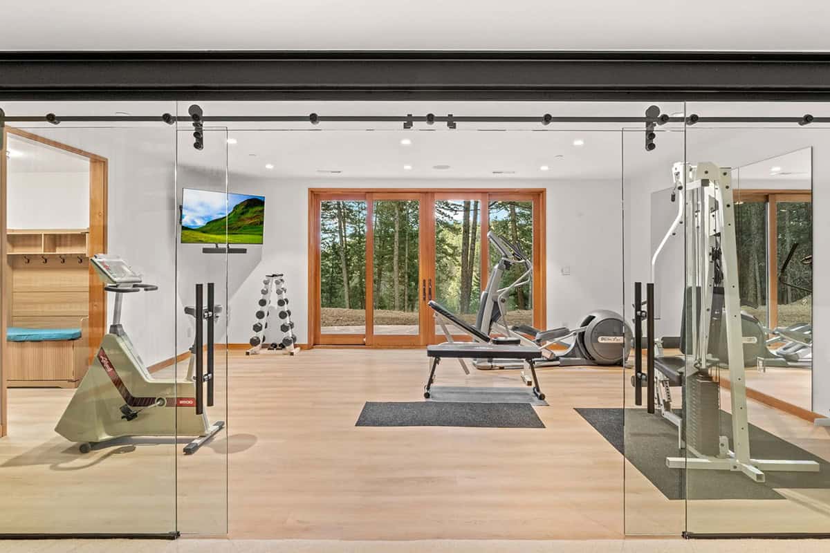 Home gym opens to forest views through glass sliding doors