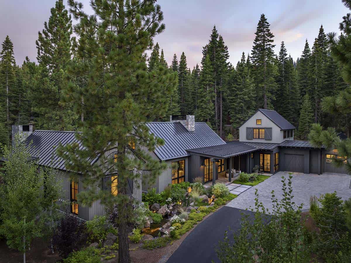 Aerial view of mountain house nestled among pine trees with paver driveway