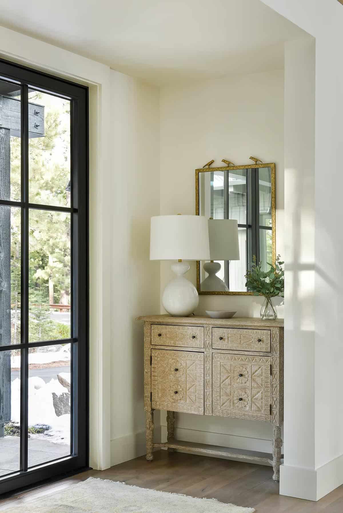 Entryway nook with carved wood console table, gold mirror, and table lamp