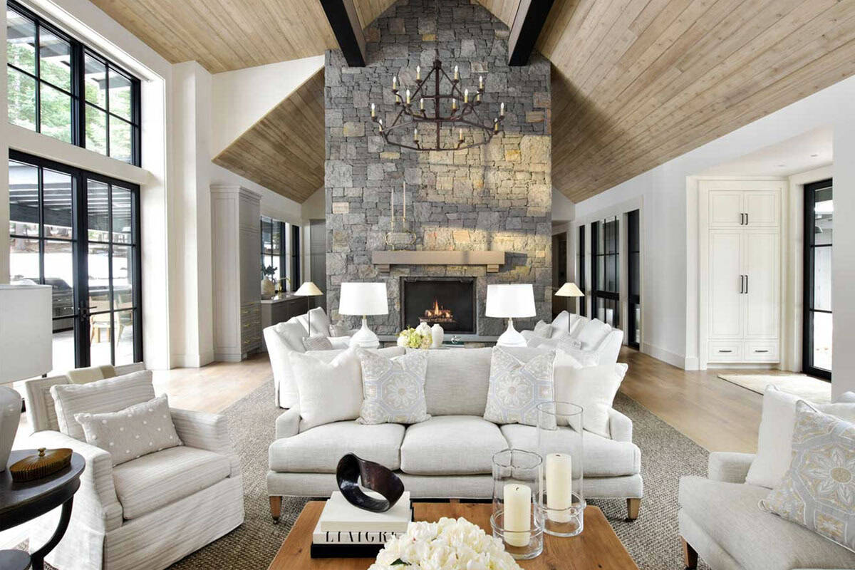 Great room with two-story stone fireplace, wood ceiling, and white sofas