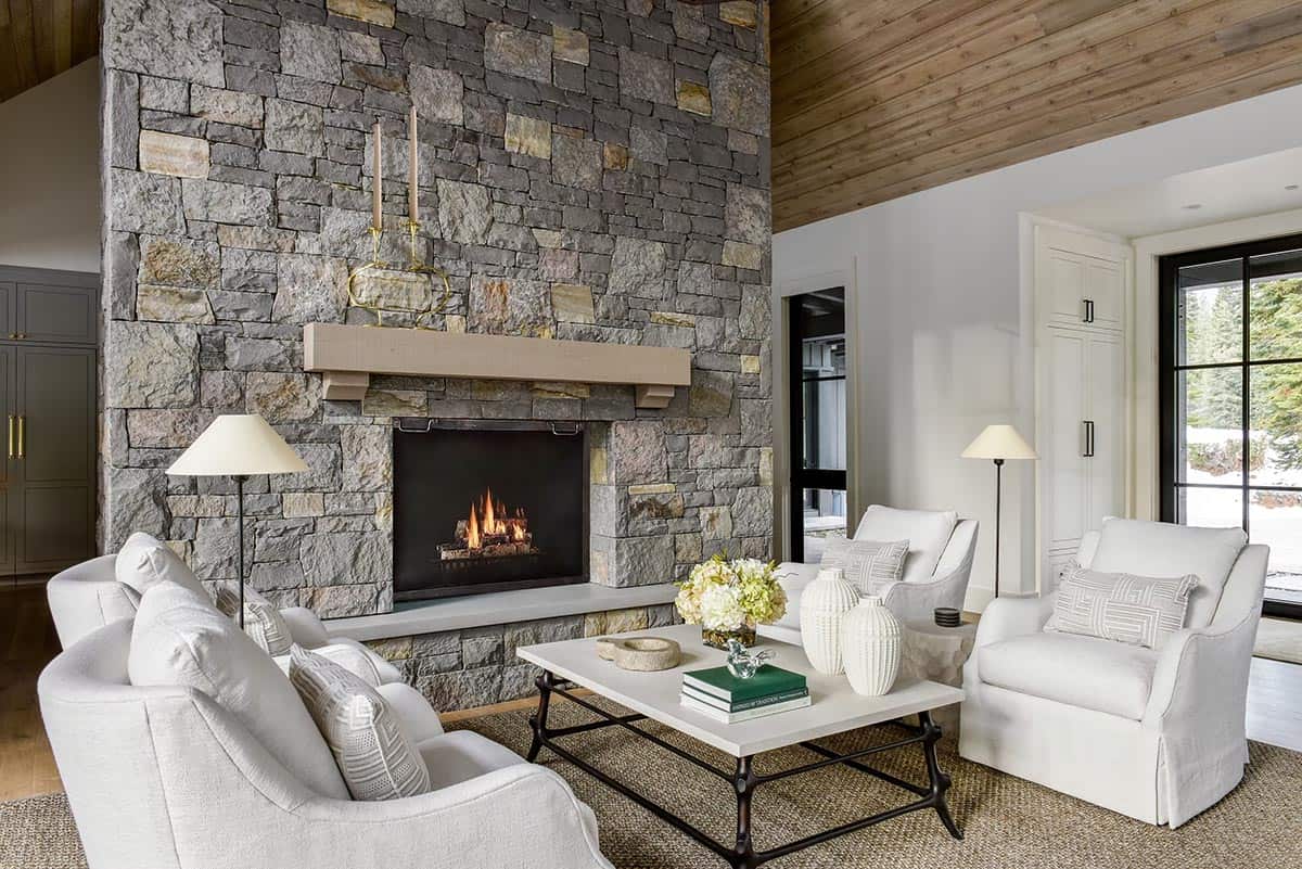 Close-up of stone fireplace with white armchairs and coffee table
