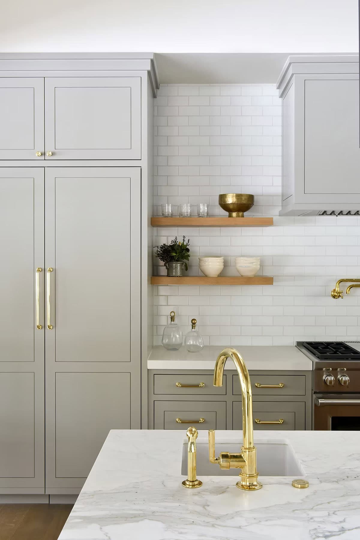 Kitchen detail with brass faucet, subway tile backsplash, and open wood shelving