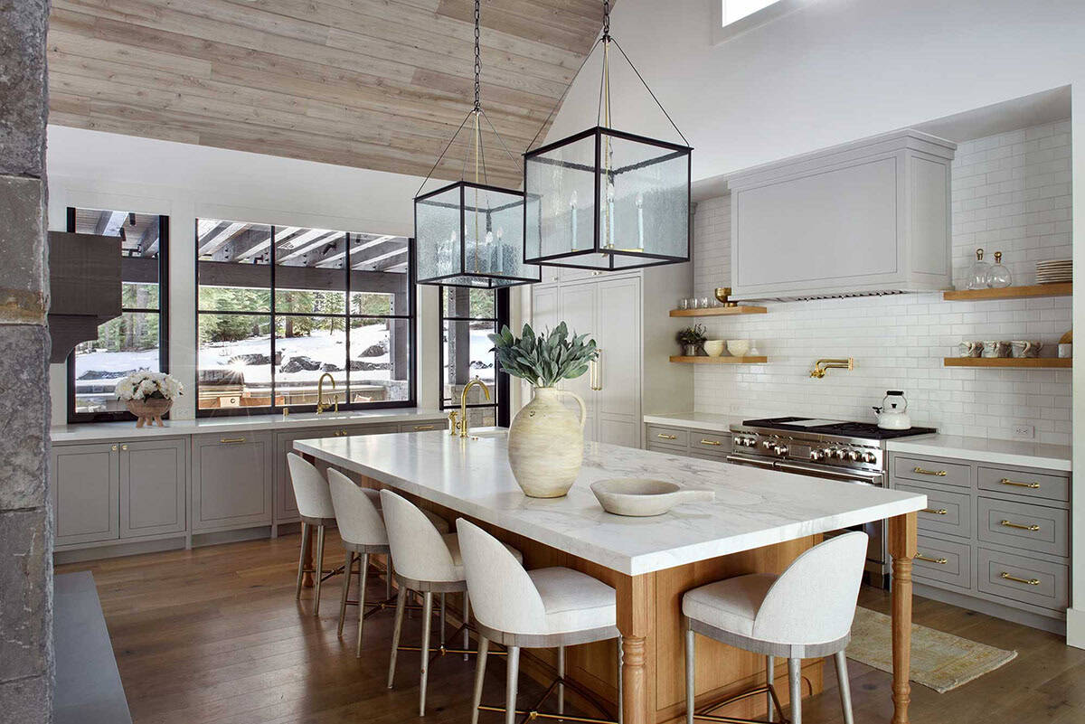 Kitchen with large island, upholstered stools, and glass lantern pendants