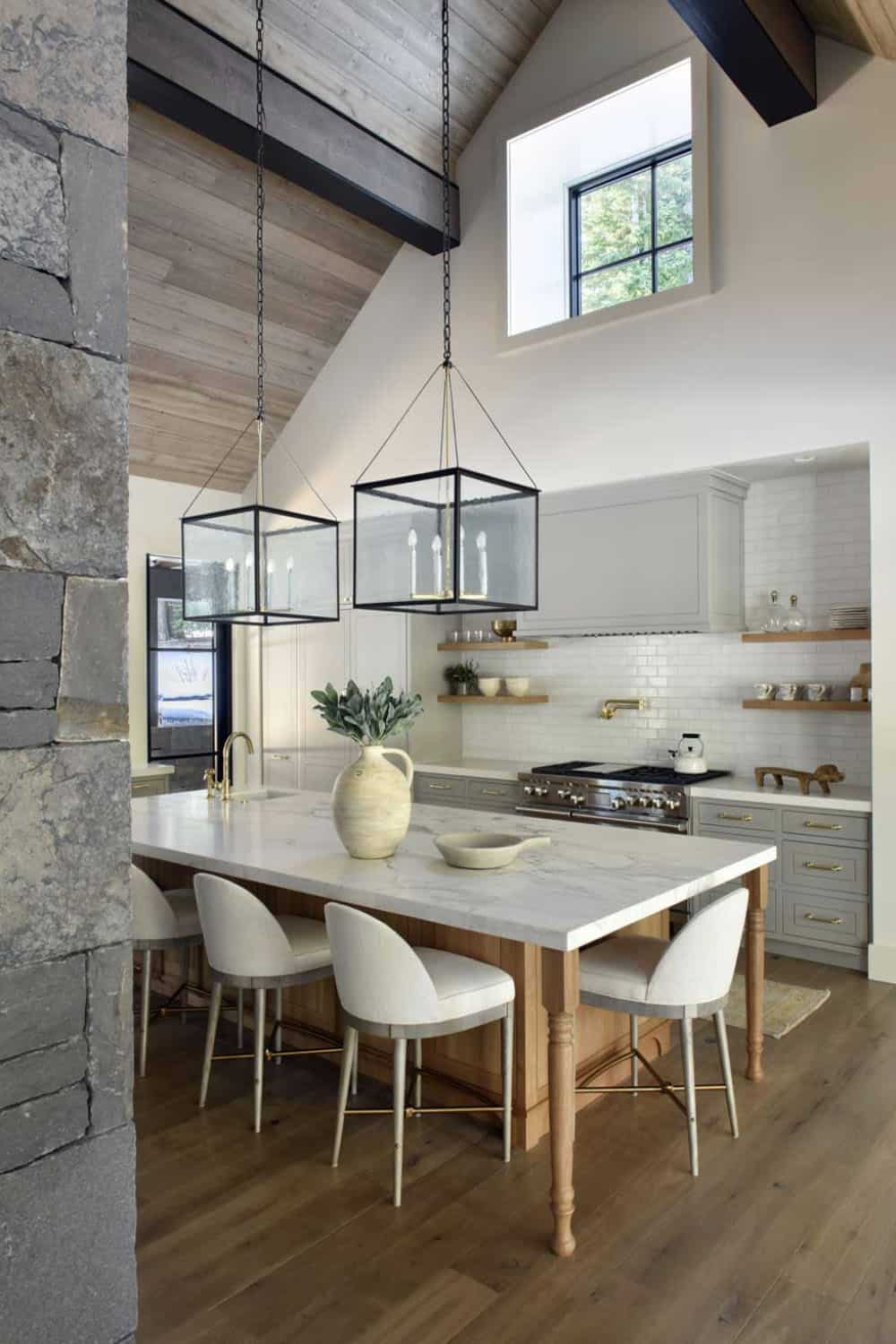 Kitchen island with wood barstools, brass fixtures, and vaulted wood ceiling