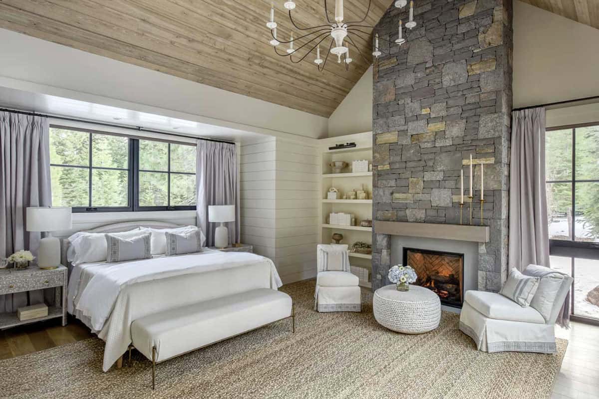 Primary bedroom with vaulted wood ceiling, stone fireplace, and sitting area