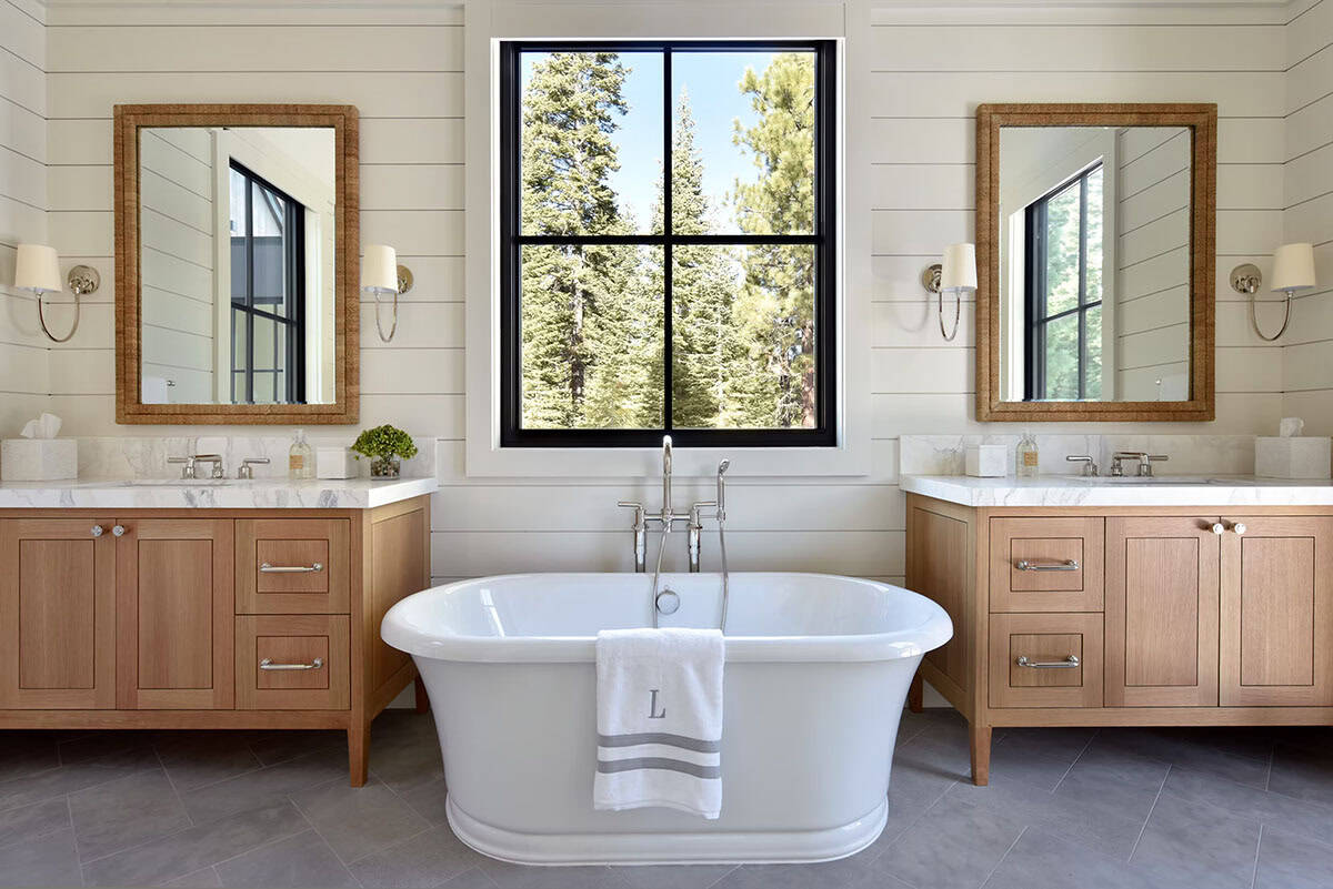Primary bathroom with dual wood vanities and freestanding soaking tub