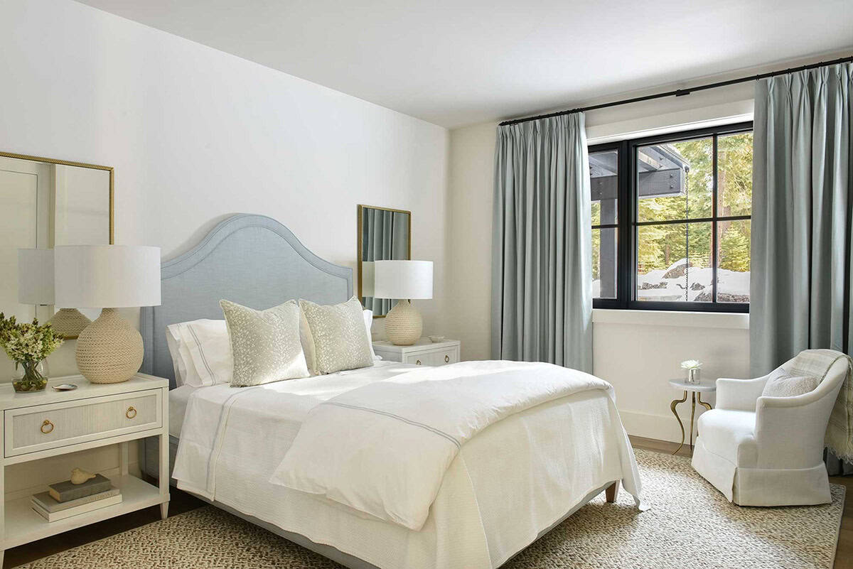 Guest bedroom with blue upholstered headboard and sage green curtains