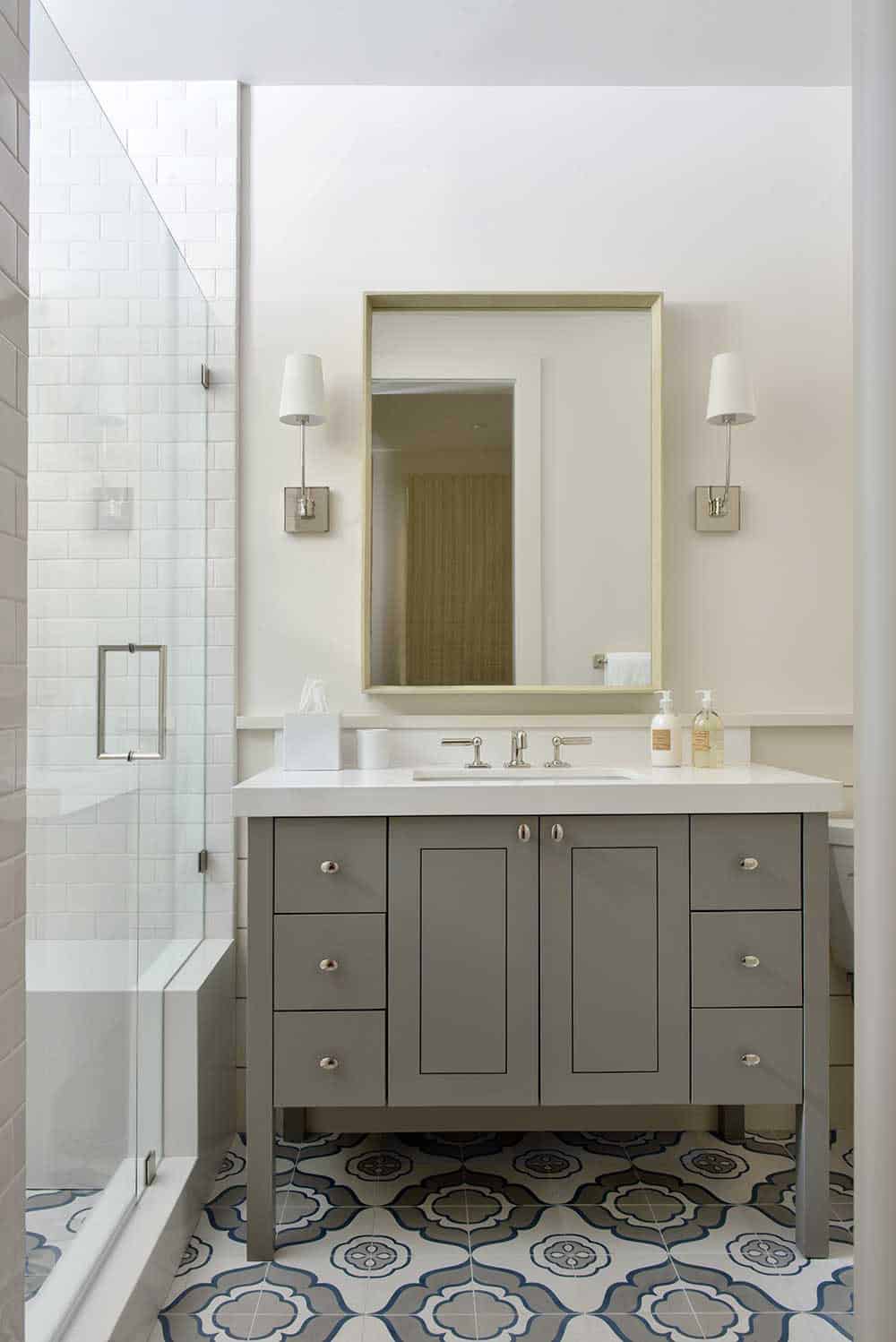 Bathroom with gray vanity, glass shower, and patterned tile floor