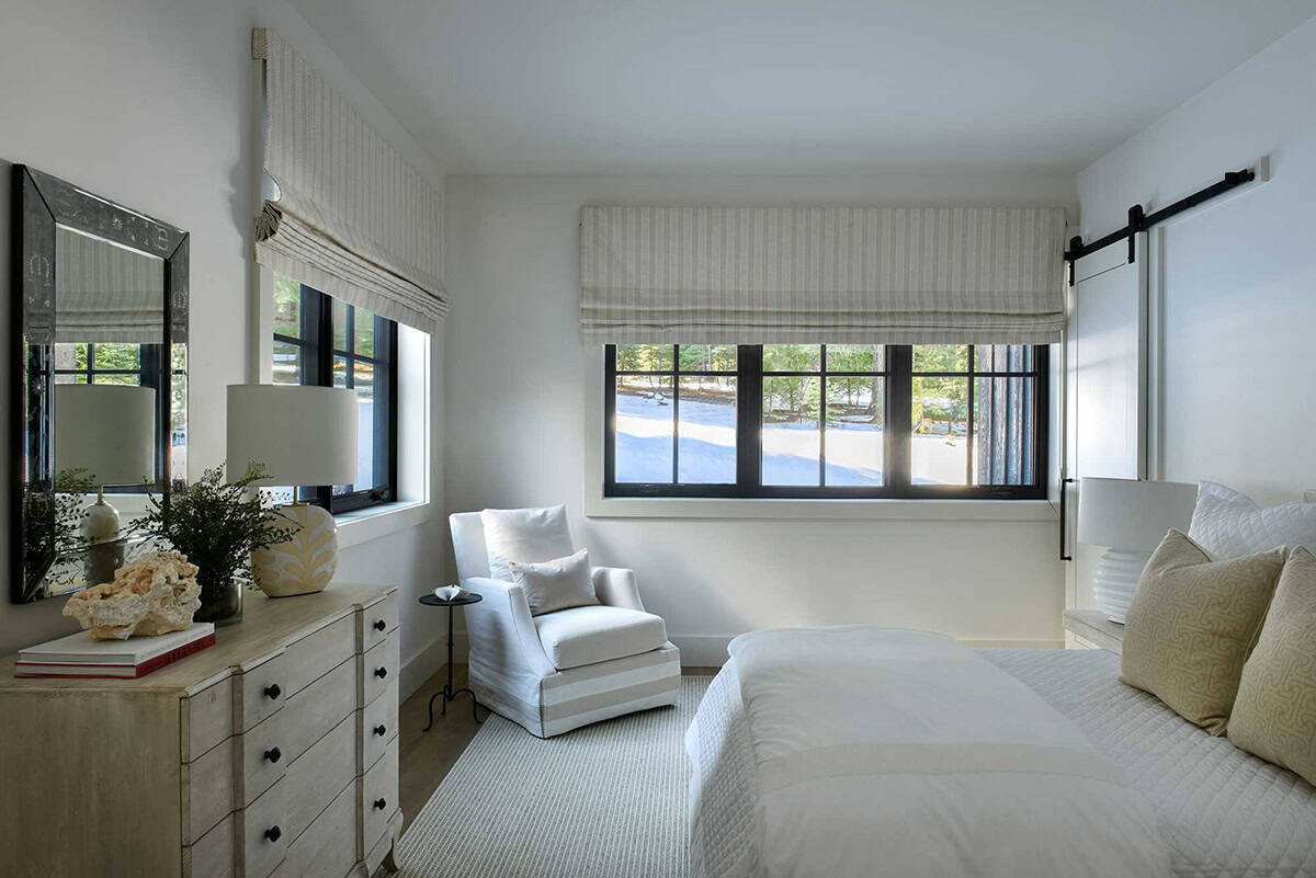 Bedroom with barn door, striped roman shades, and dresser vignette