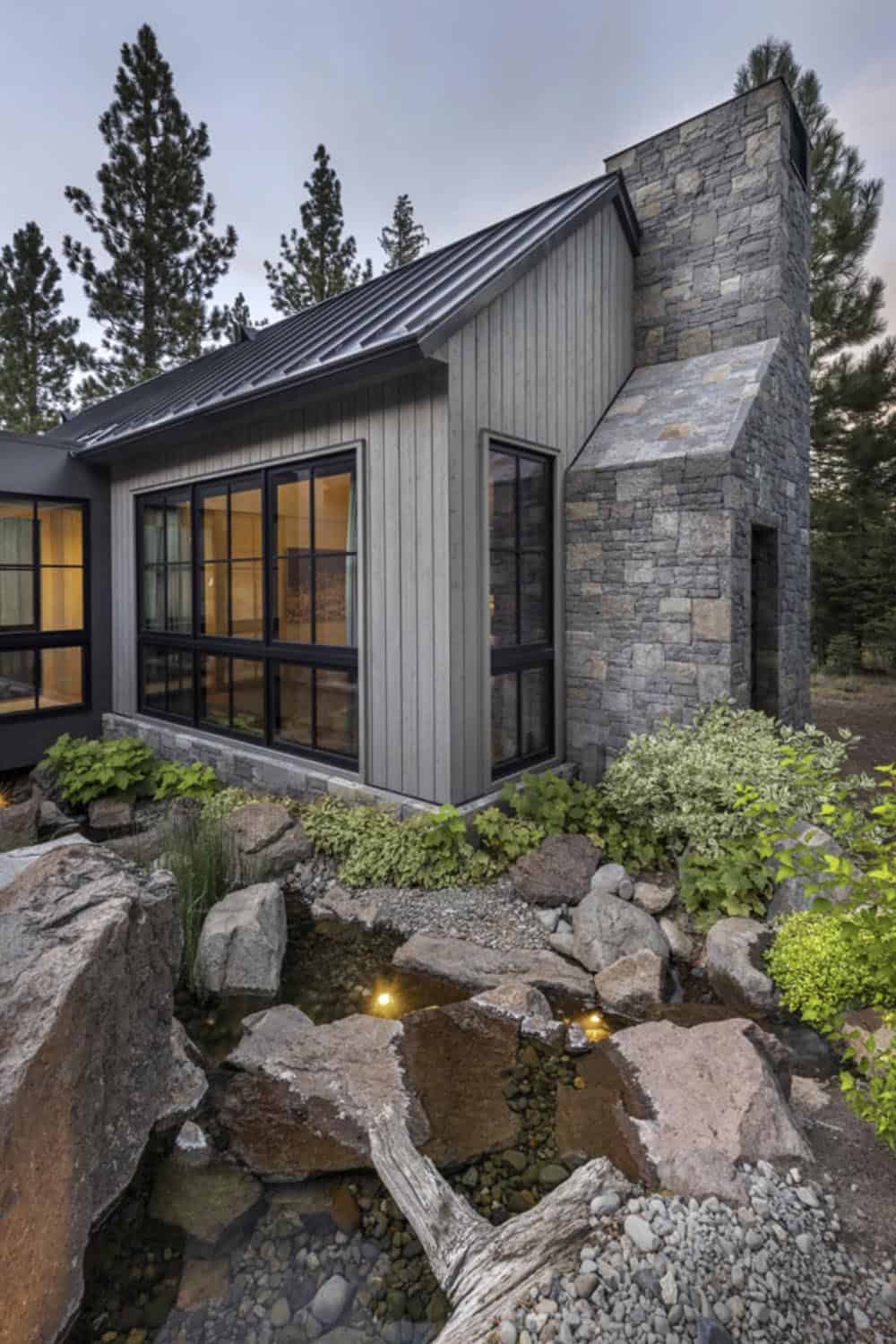Exterior corner detail showing stone chimney and board-and-batten siding at dusk