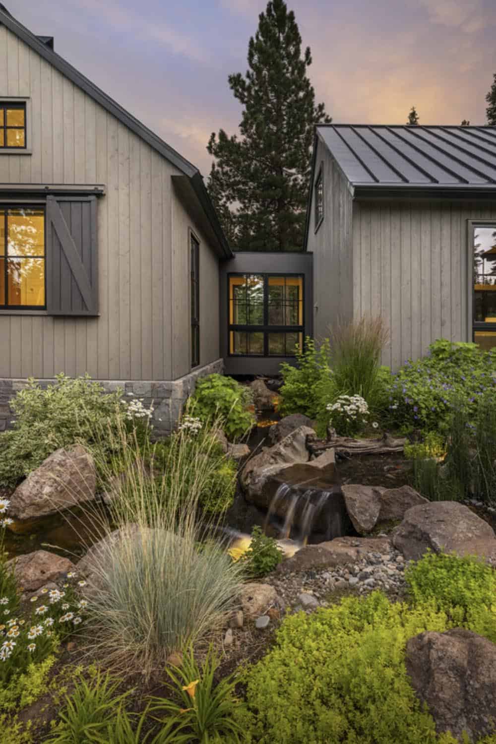 Exterior view of house connected by glass breezeway with stream feature at sunset